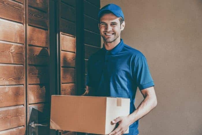 A smiling delivery man holding a parcel in his hands