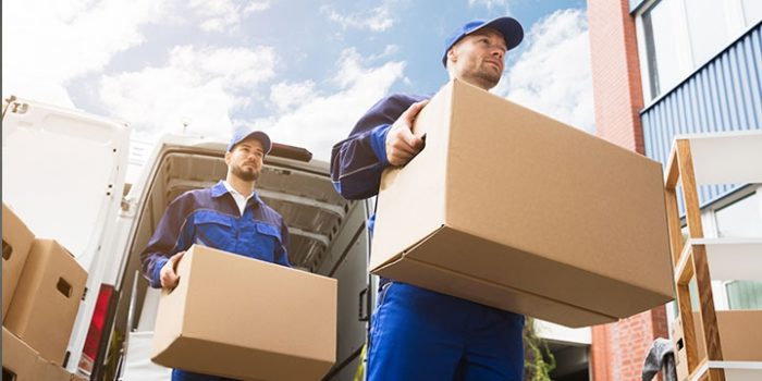 Two delivery men carrying parcels from a van