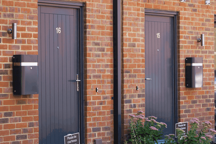 Two black letter boxes mounted on the wall in front of two doors