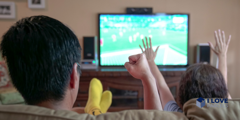 Two people watching soccer on tv